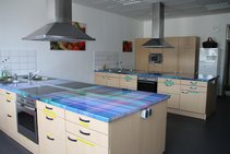 Blick in die Lehrküche der vhs Straubing - vier vollausgestattete Kochzeilen mit bunter Arbeitsplatte und Dunstabzug